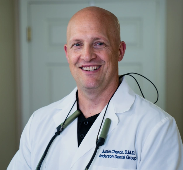 Smiling male dentist wearing a white dental coat